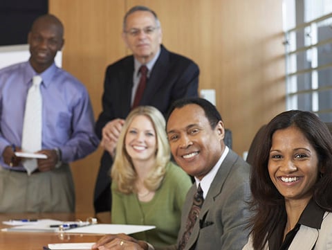 Diverse group of business men and women sitting around a conference table