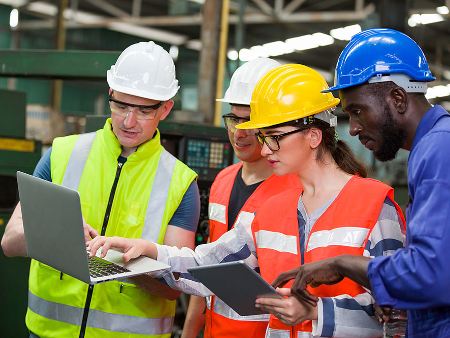 workers wearing hard hats, reflective vests with laptop